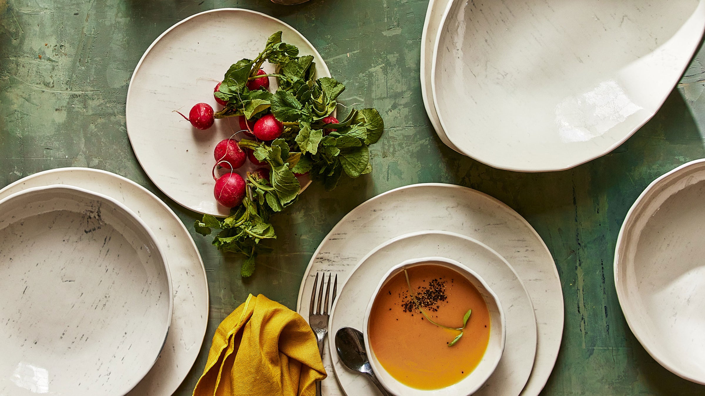 Image of DBO Home porcelain tableware pieces with organic birch pattern on green table