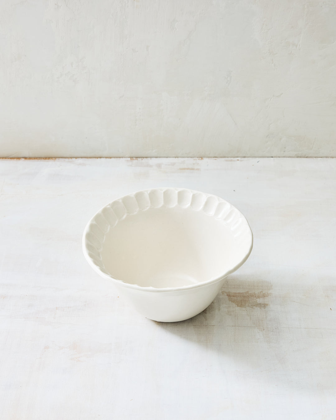 DBO HOME Nonna Small Bowl in creamy porcelain with shimmering Snowflake glaze and soft fluting along the rim. A versatile handmade piece that feels equally at home on a breakfast table or in a formal setting.