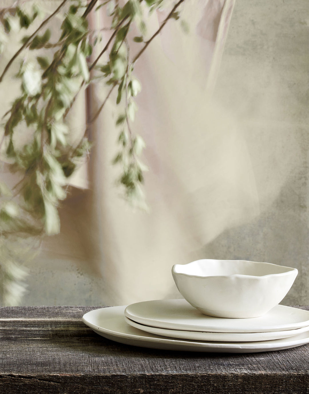 DBO HOME artisan ceramic salad plates and dinner plate stacked with porcelain bowl on natural wooden table with soft background