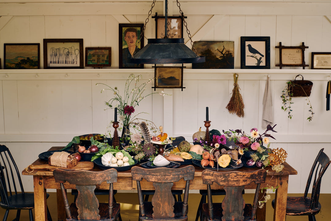 A rustic wooden table set for fall from a recent Tastemakers' Table story photographed by John Gruen, styled with DBO Home ceramics, seasonal vegetables, seasonal florals by Romane Recalde