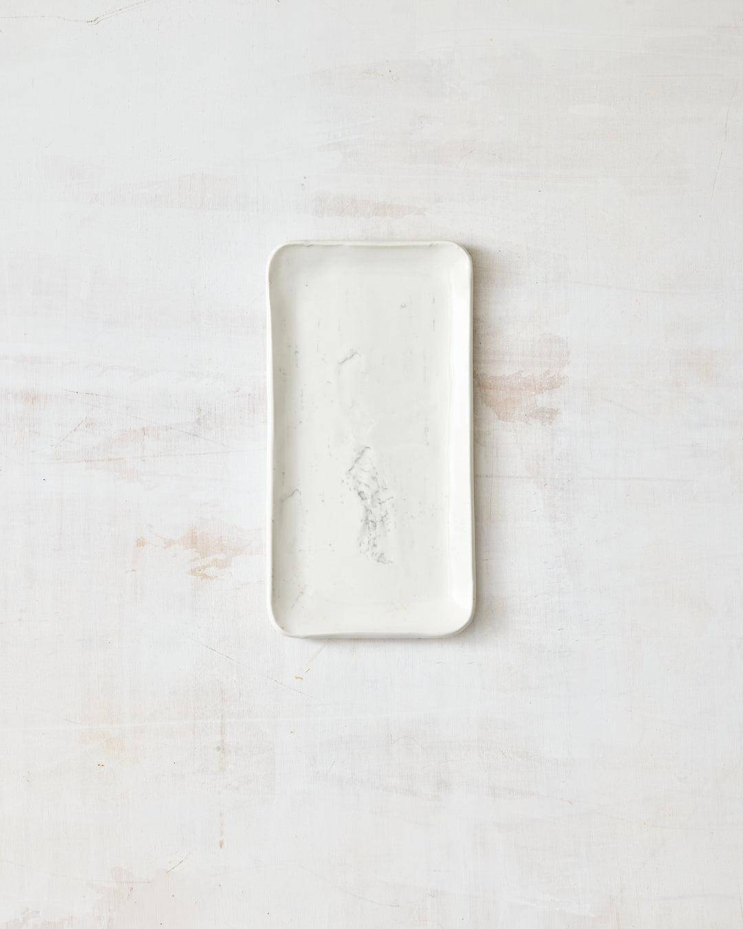 A small handmade porcelain plate from DBO Home's Birch collection, featuring a Salt n Pepper glaze and birch bark-impressed texture, photographed overhead on a white painted wood surface