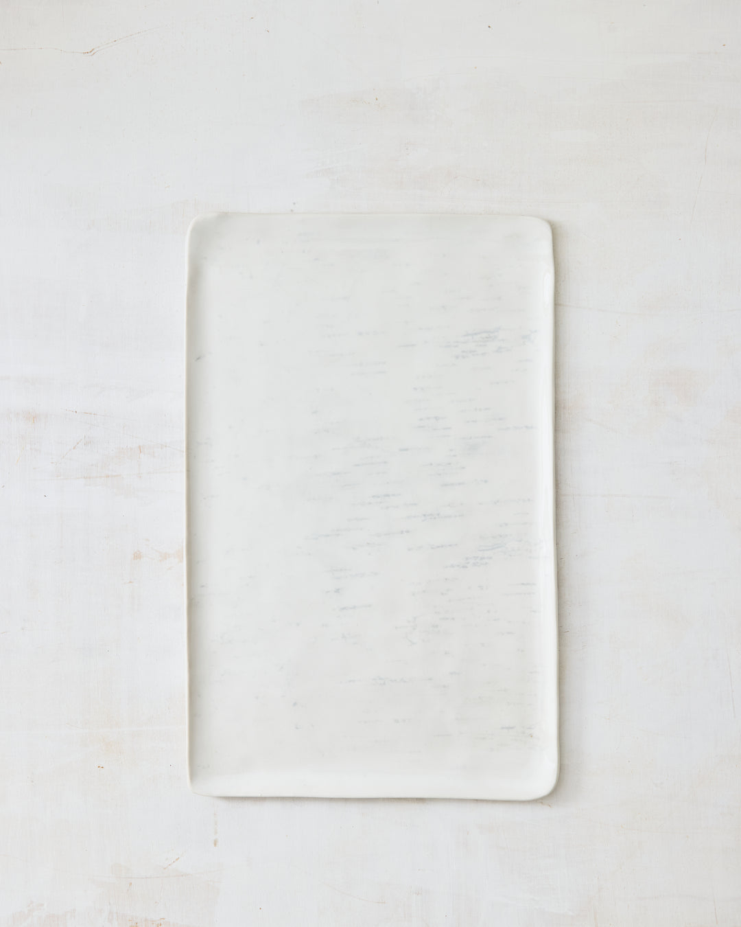 A large rectangular artisan ceramic platter from DBO Home's Birch collection in Salt n Pepper glaze, with softly rounded corners and birch bark-impressed texture, photographed overhead on a white painted wood surface