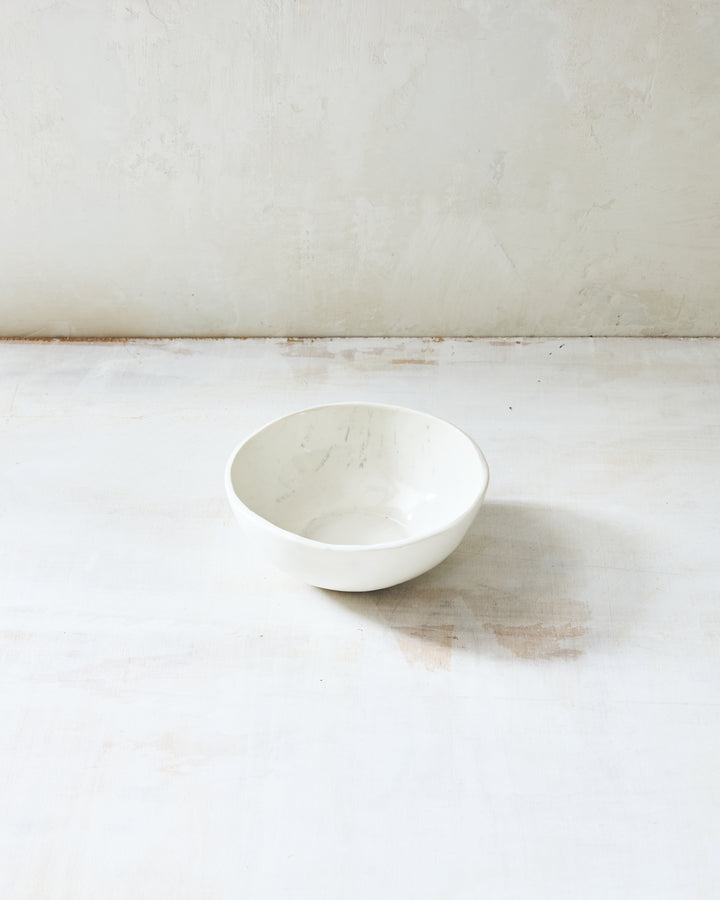 A small handmade porcelain soup bowl from DBO Home's Birch collection in Salt n Pepper glaze, with birch bark-impressed interior texture, photographed at a low angle on a whitewashed surface