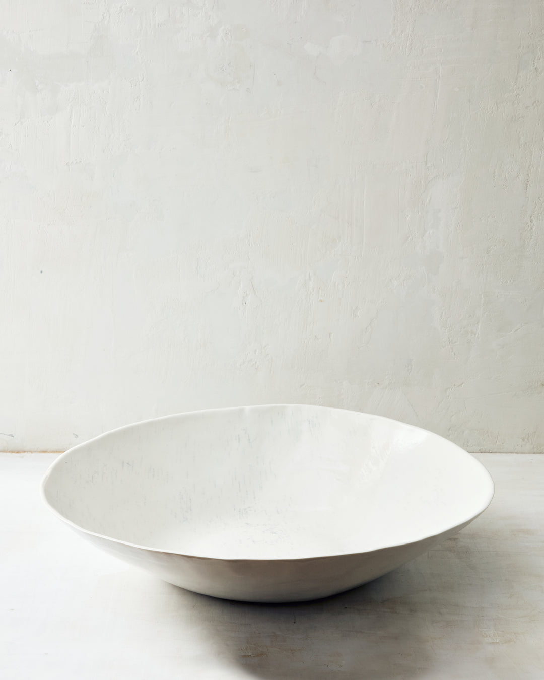 An extra-large handmade porcelain bowl from DBO Home's Birch collection in Salt n Pepper glaze, with a wide organic rim and a glossy interior, textured with impressed birch bark, photographed at a low angle against a whitewashed wall