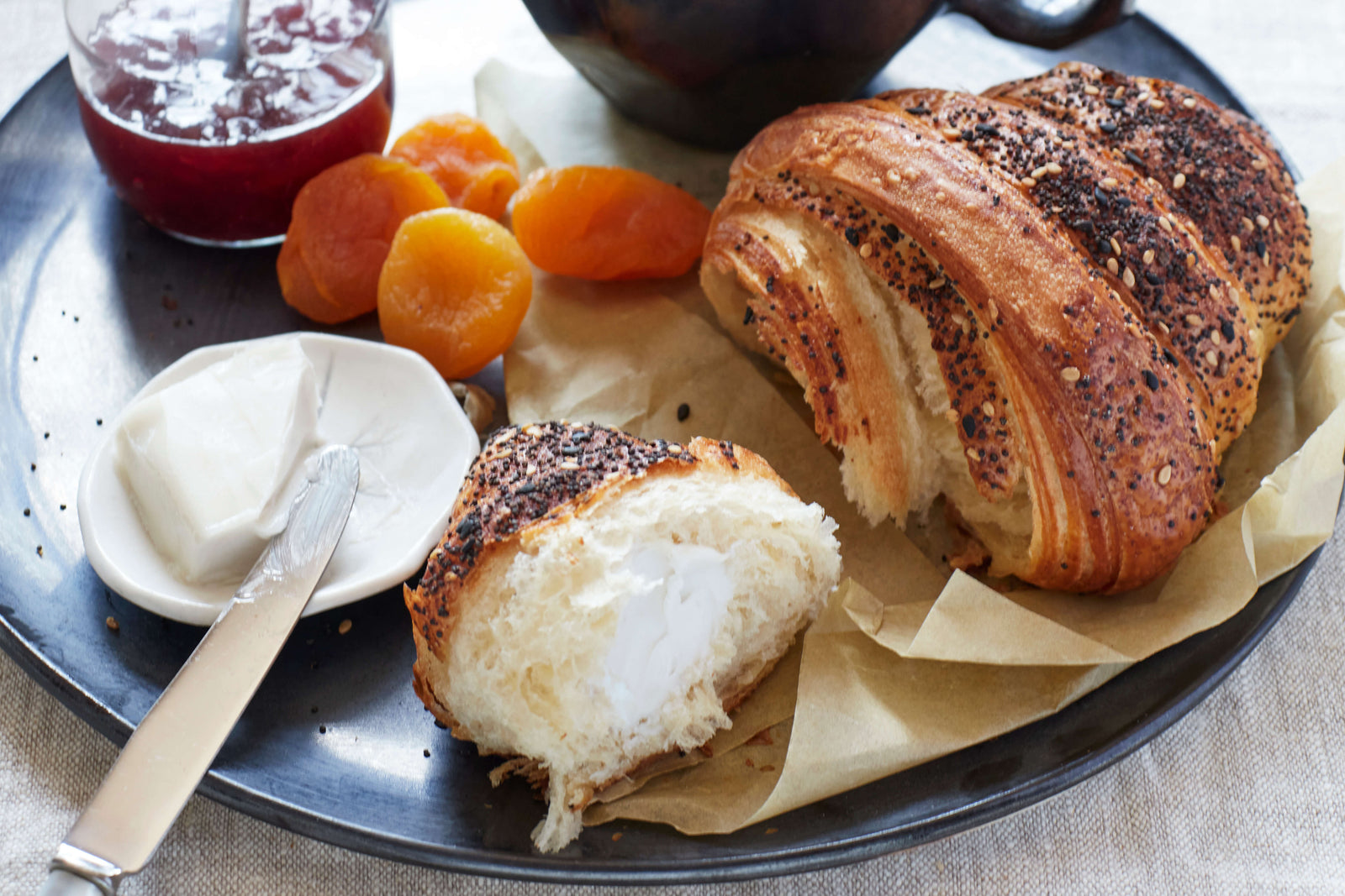 Torn open croissant from Bourke Street Bakery with cream cheese on a DBO Home Bare Salad Plate with fruit and jam