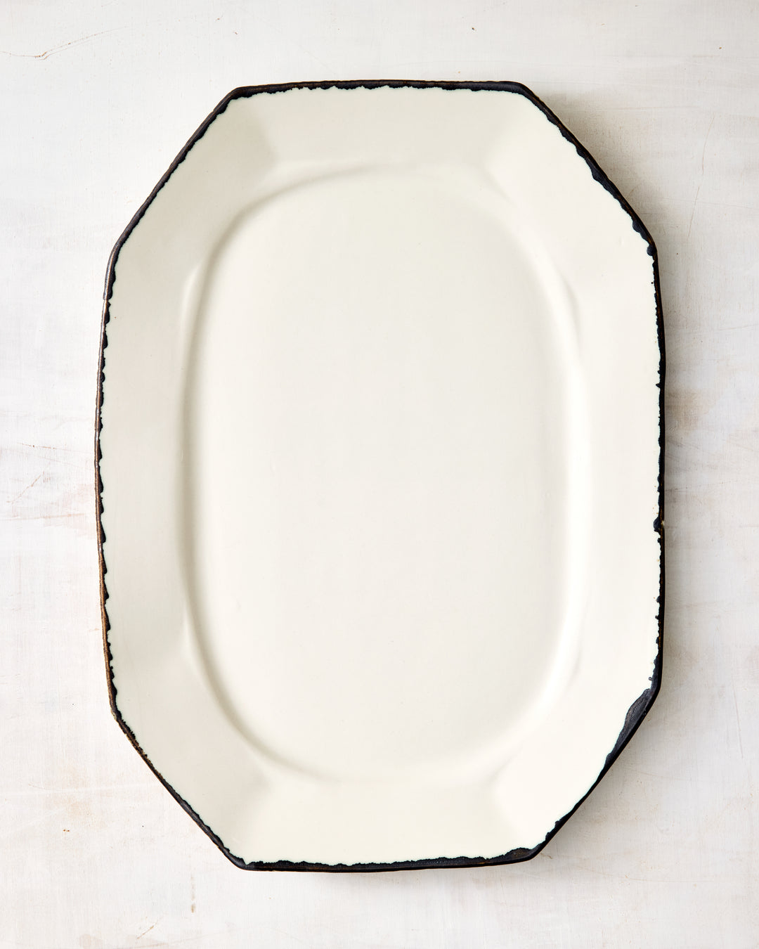 DBO HOME Formale Platter in creamy porcelain with a hand-applied bronze glaze edge. The faceted silhouette and smooth surface offer a quietly elegant base for serving or display.