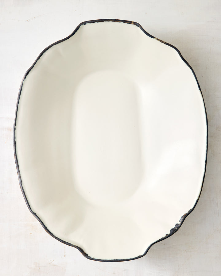 Top view of the Formale Serving Bowl by DBO HOME, crafted in creamy porcelain with a bronze-edge glaze. The curved, faceted silhouette is both functional and sculptural.