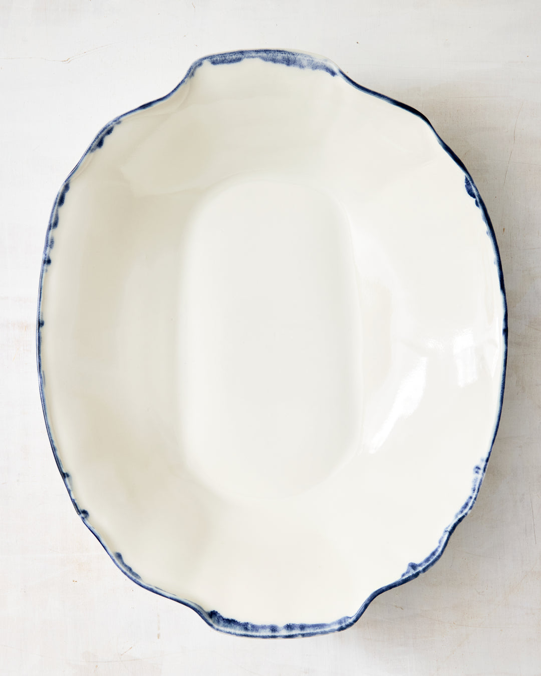 Top-down image of the DBO HOME Formale Serving Bowl in porcelain with an indigo-glazed edge. Elegant and unfussy, designed for both everyday meals and special gatherings.