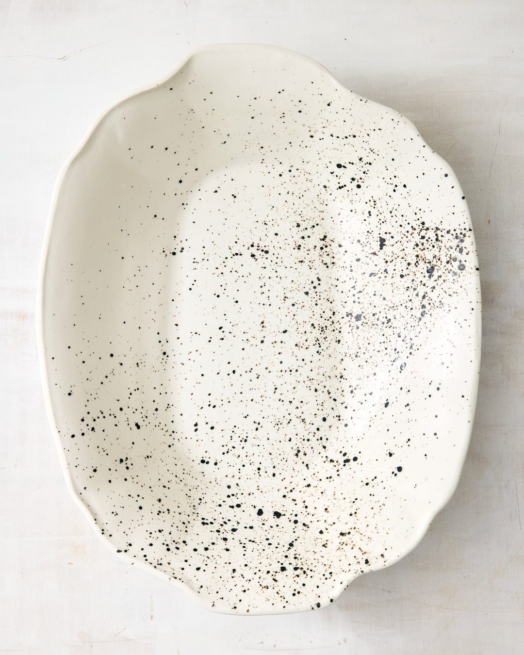DBO HOME Formale Serving Bowl in creamy porcelain with black speckled glaze, seen from above. A bold yet natural finish that adds texture to any table setting.