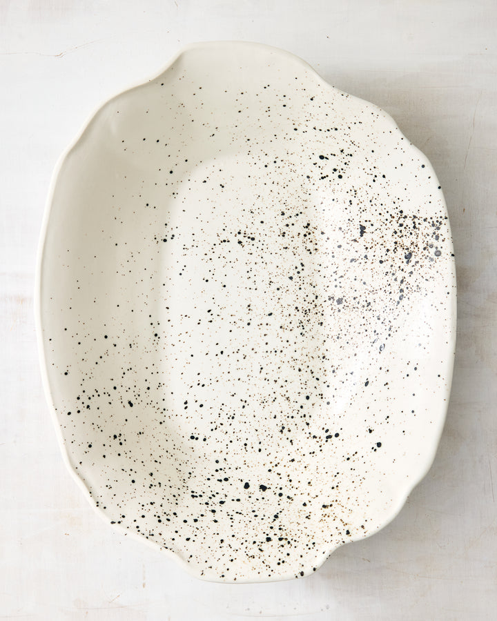 DBO HOME Formale Serving Bowl in creamy porcelain with black speckled glaze, seen from above. A bold yet natural finish that adds texture to any table setting.
