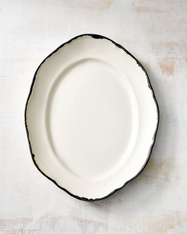DBO HOME Formale Small Platter in creamy white porcelain with a bronze rim. The softly angled edges and minimal shape make this smaller serving tray perfect for appetizers, desserts, or layering on the table.