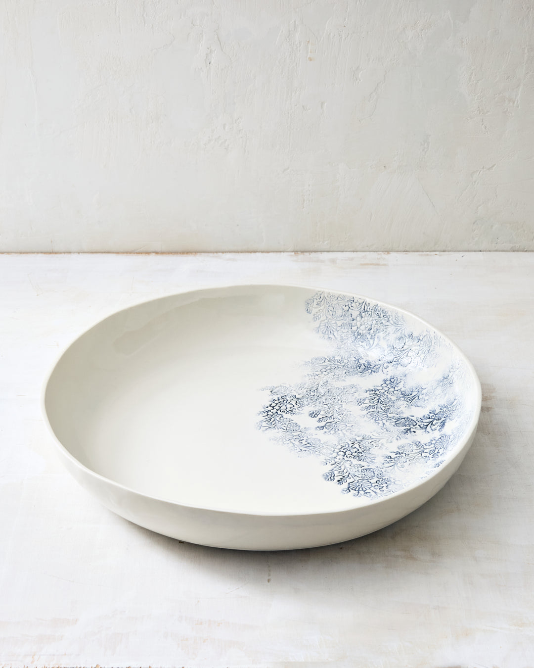 Large round porcelain bowl from the Kashmir collection, featuring an indigo floral motif on a handcrafted serving piece.