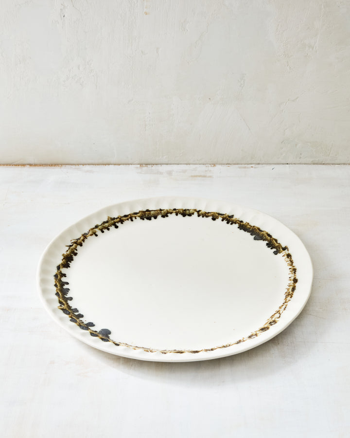 DBO HOME Nonna Dinner Plate in Snowflake porcelain with a hand-applied bronze glaze rim, shown on a softly textured white surface.