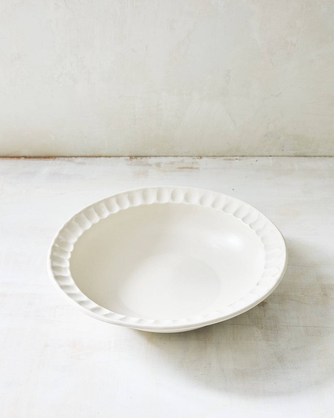 DBO HOME Nonna Pasta Bowl in warm white porcelain with a softly scalloped rim. Coated in Snowflake glaze over porcelain, this handmade ceramic bowl brings understated elegance to everyday dining.