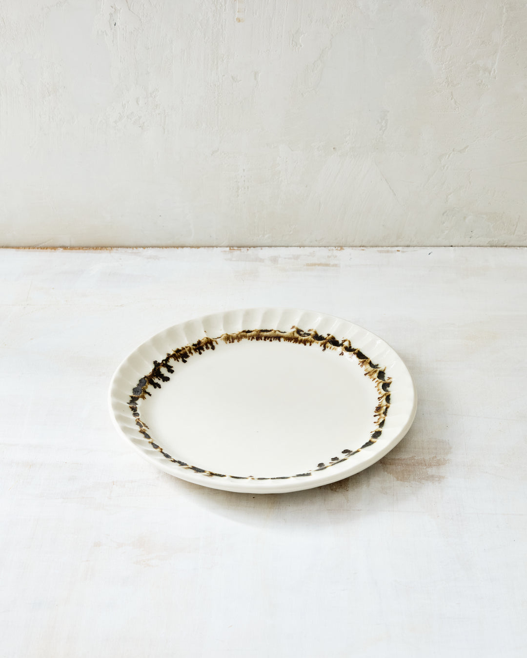 DBO HOME Nonna Salad Plate in creamy porcelain with hand-applied bronze glaze along the fluted rim. The organic drip pattern adds tactile charm and a sense of movement to this heirloom-quality ceramic plate.