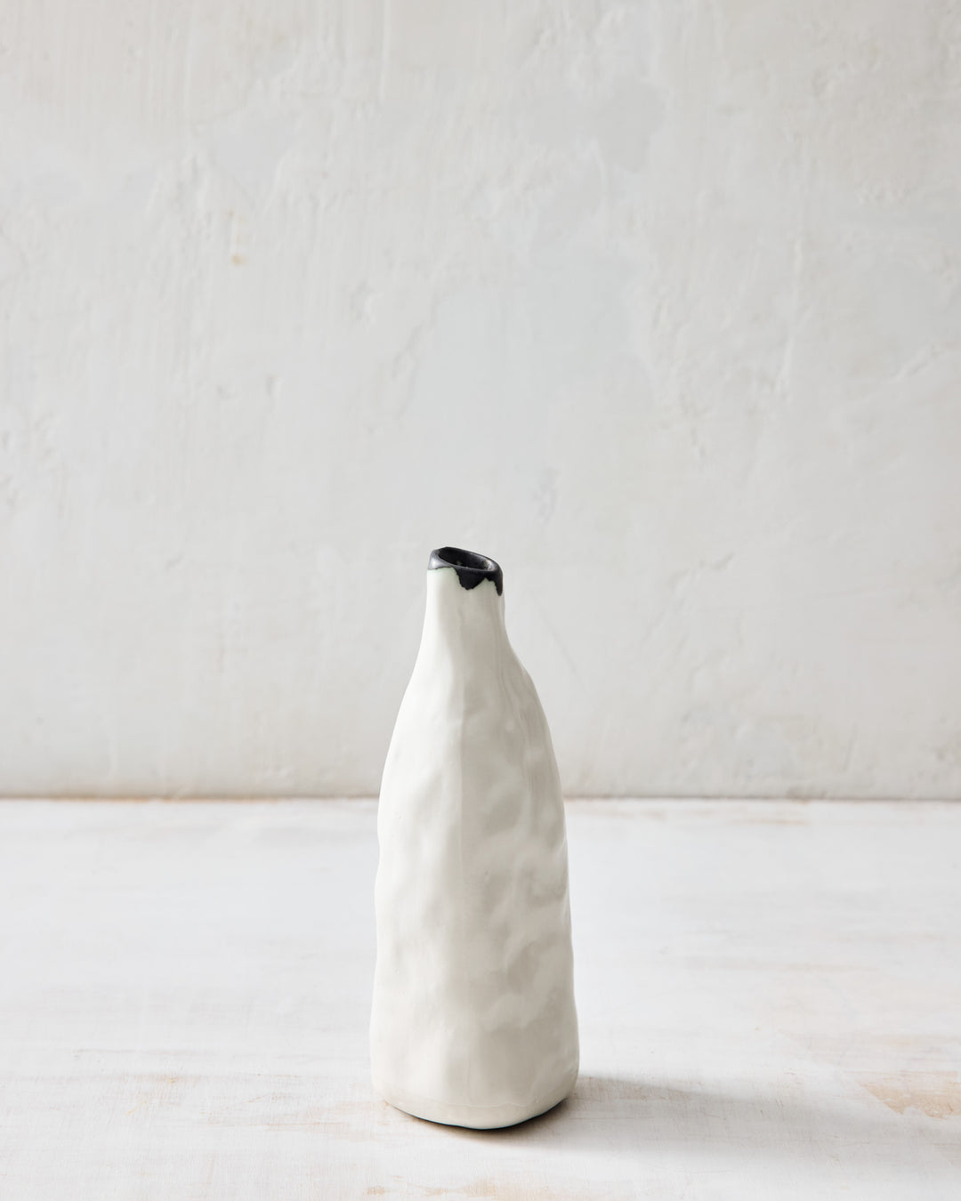 DBO HOME Pinch Bud Vase – George in creamy white porcelain with a raw bronze-dipped rim. Tall and subtly faceted with a hand-pinched texture, this ceramic bud vase brings a sculptural quiet to any shelf or tabletop.