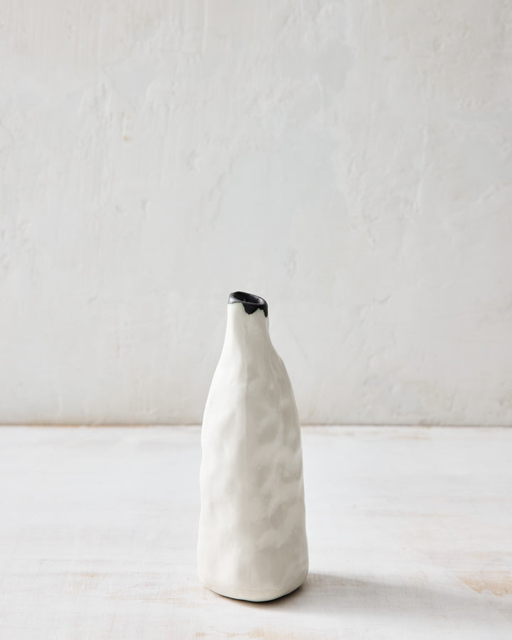 DBO HOME Pinch Bud Vase – George in creamy white porcelain with a raw bronze-dipped rim. Tall and subtly faceted with a hand-pinched texture, this ceramic bud vase brings a sculptural quiet to any shelf or tabletop.