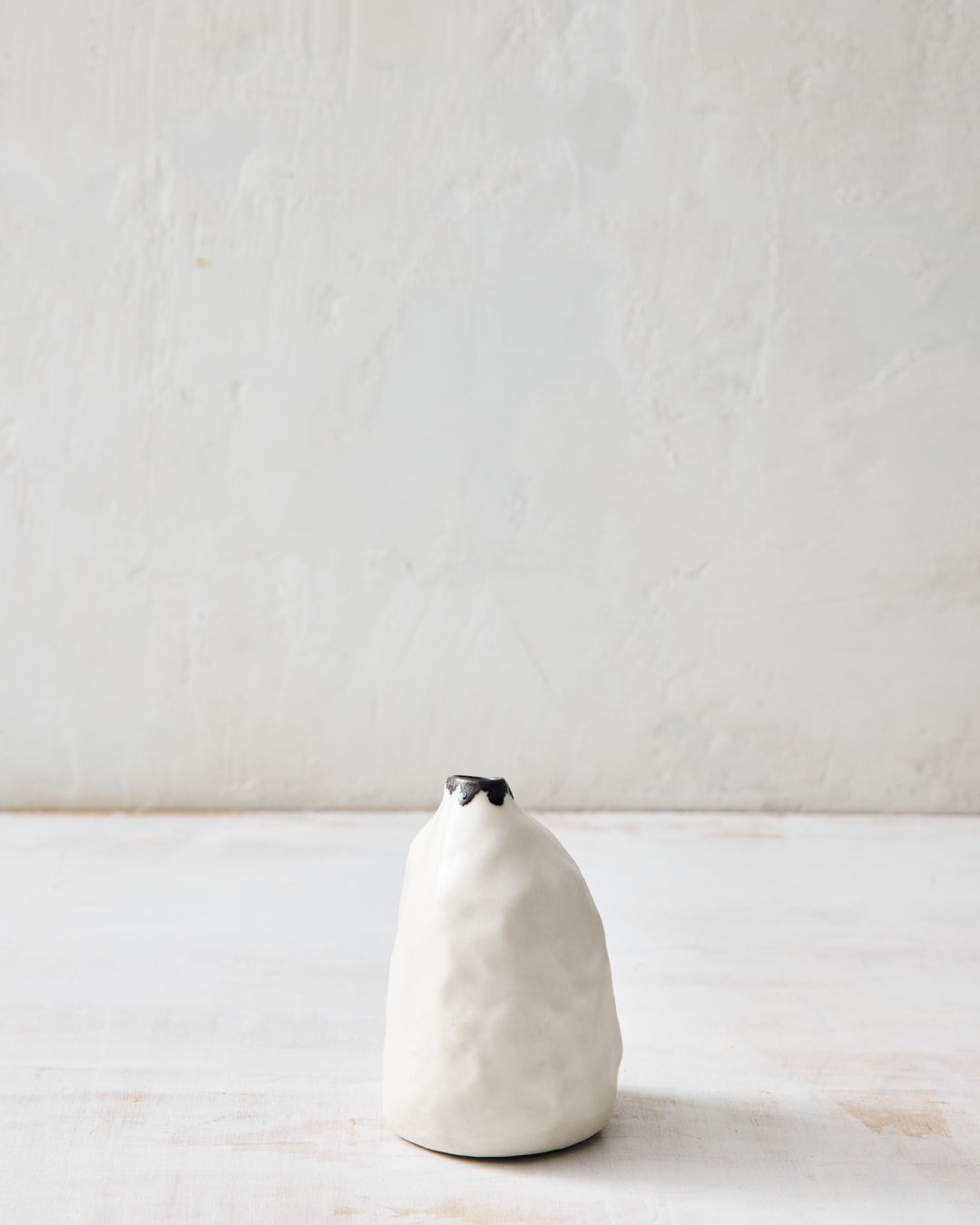 Side profile of the Pinch Bud Vase – Paul from DBO HOME, highlighting its softly asymmetrical shape and hand-formed silhouette in white porcelain with a bronze detail at the lip.
