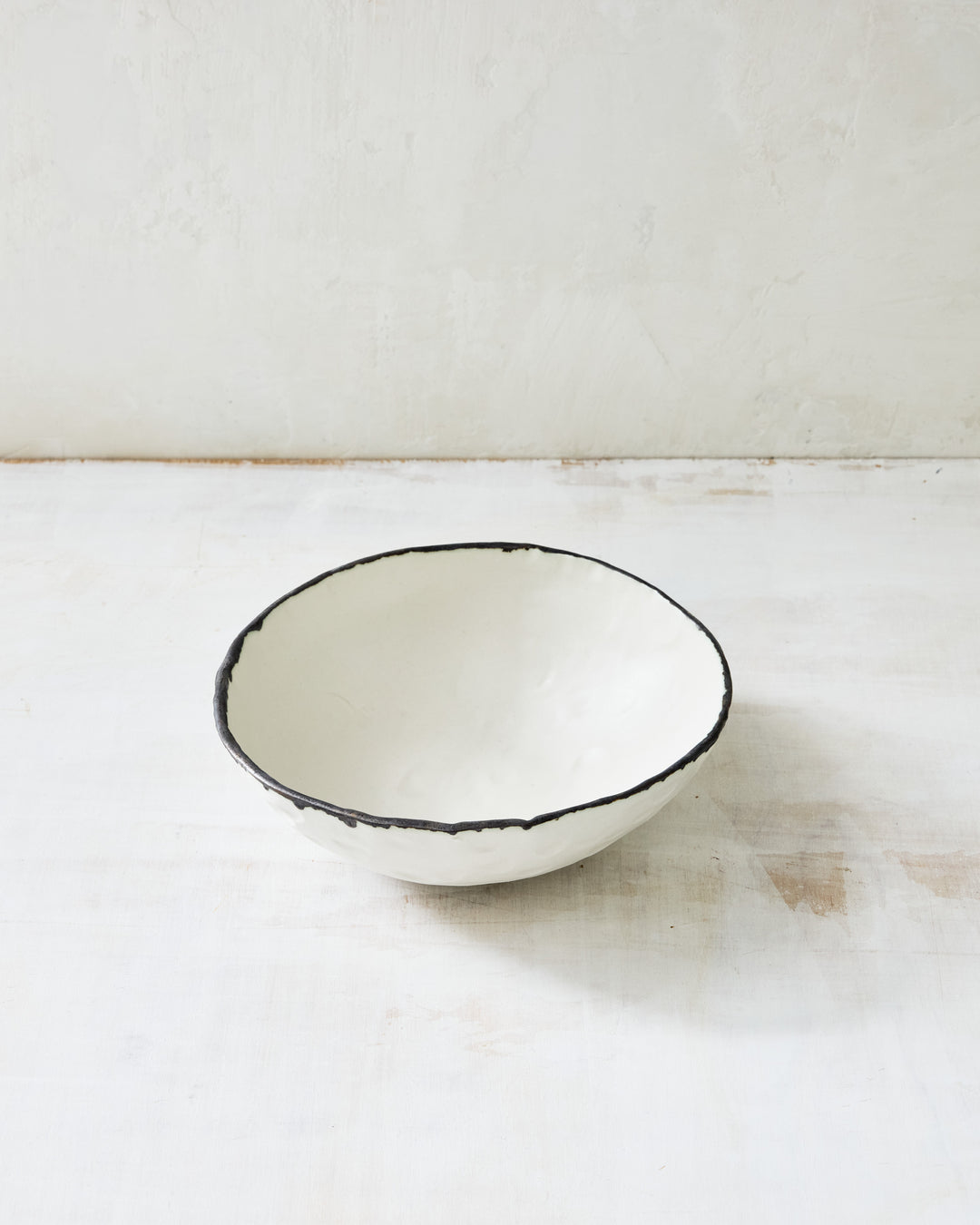 DBO HOME Pinch Noodle Bowl in hand-thrown porcelain with a dark bronze rim. Deeper and slightly flared, this artisanal ceramic bowl is perfect for ramen, pasta, or cozy one-bowl meals. Shown on a minimal white backdrop.