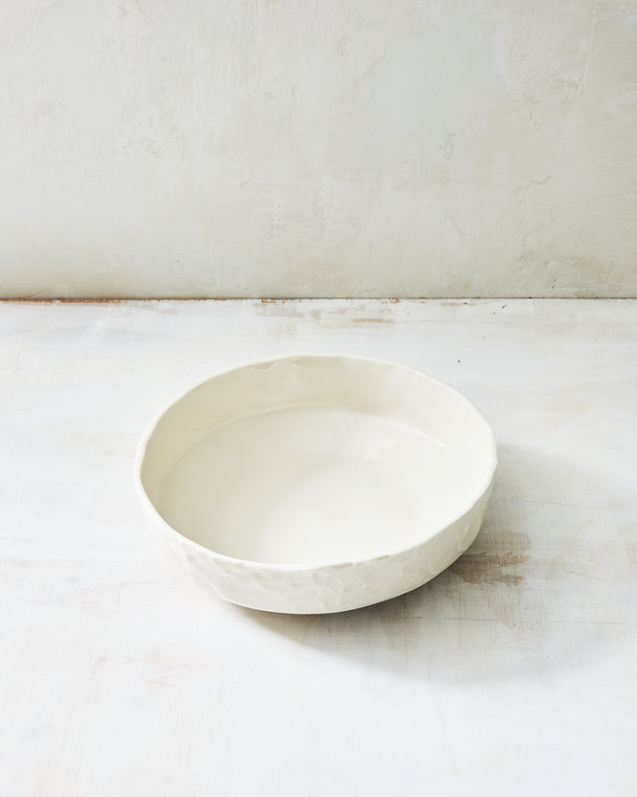 DBO HOME Stucco Everything Bowl in clear-glazed handmade porcelain with a wide, shallow form and tactile stucco-textured exterior, photographed on a whitewashed surface.