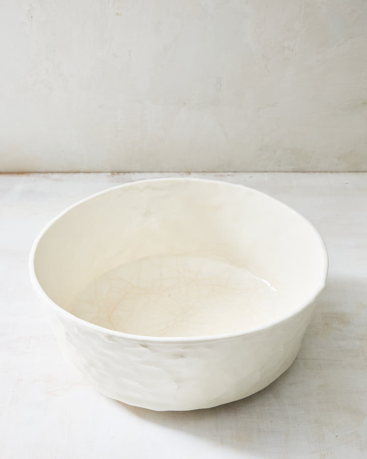 DBO HOME Stucco Salad Bowl in clear-glazed handmade porcelain with a tactile stucco-textured exterior, angled view showing the clean interior, photographed on a whitewashed surface.