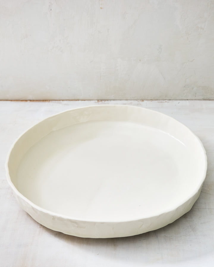 DBO HOME Stucco Serving Bowl in clear-glazed handmade porcelain with a wide, low-profile form and tactile stucco-textured exterior, photographed on a whitewashed surface.