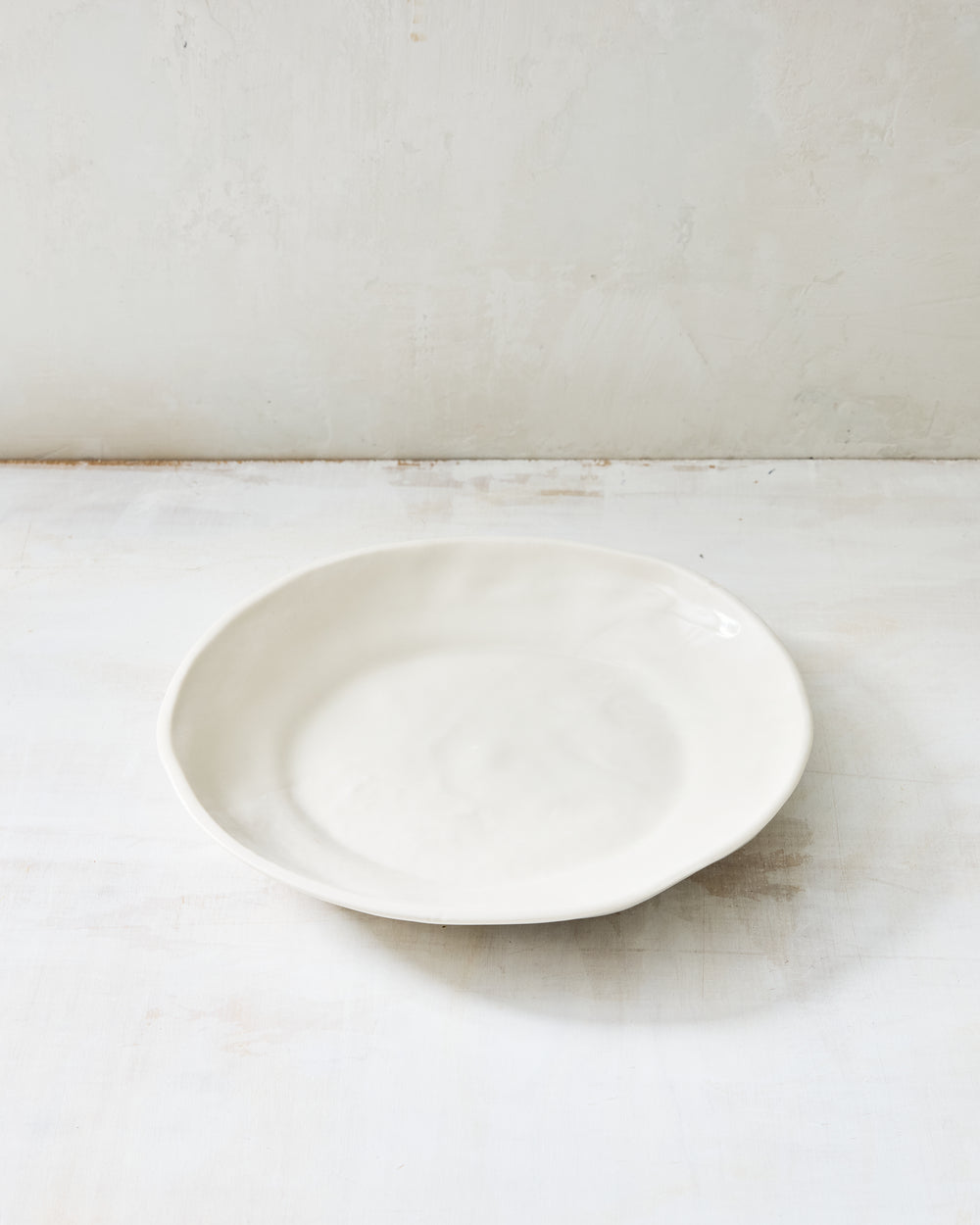 DBO HOME Wabi Pasta Bowl in Foam glaze, handmade porcelain with a wide shallow form, subtle white-on-white layered glaze, and a stone-like surface texture, photographed on a whitewashed surface.