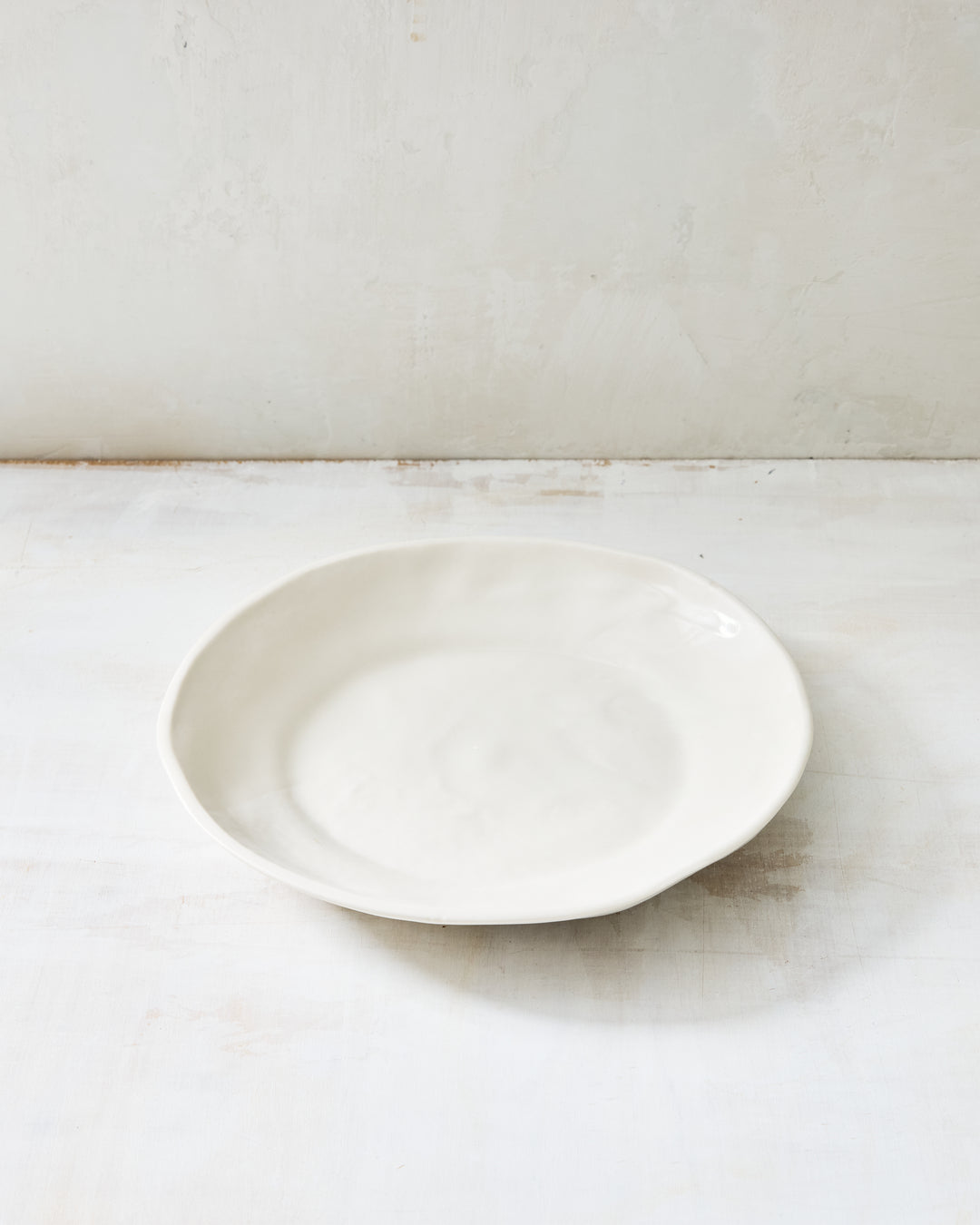 DBO HOME Wabi Pasta Bowl in Foam glaze, handmade porcelain with a wide shallow form, subtle white-on-white layered glaze, and a stone-like surface texture, photographed on a whitewashed surface.