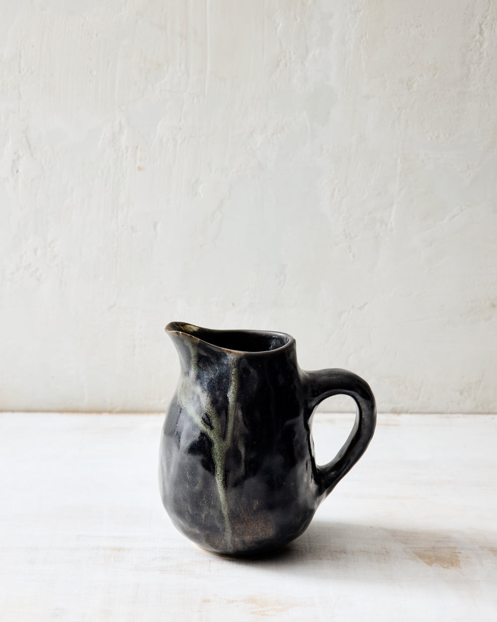 DBO HOME Wabi Pitcher in Granite glaze, handmade porcelain with a layered mussel and snowflake glaze and stone-like surface texture, front view on a whitewashed surface.