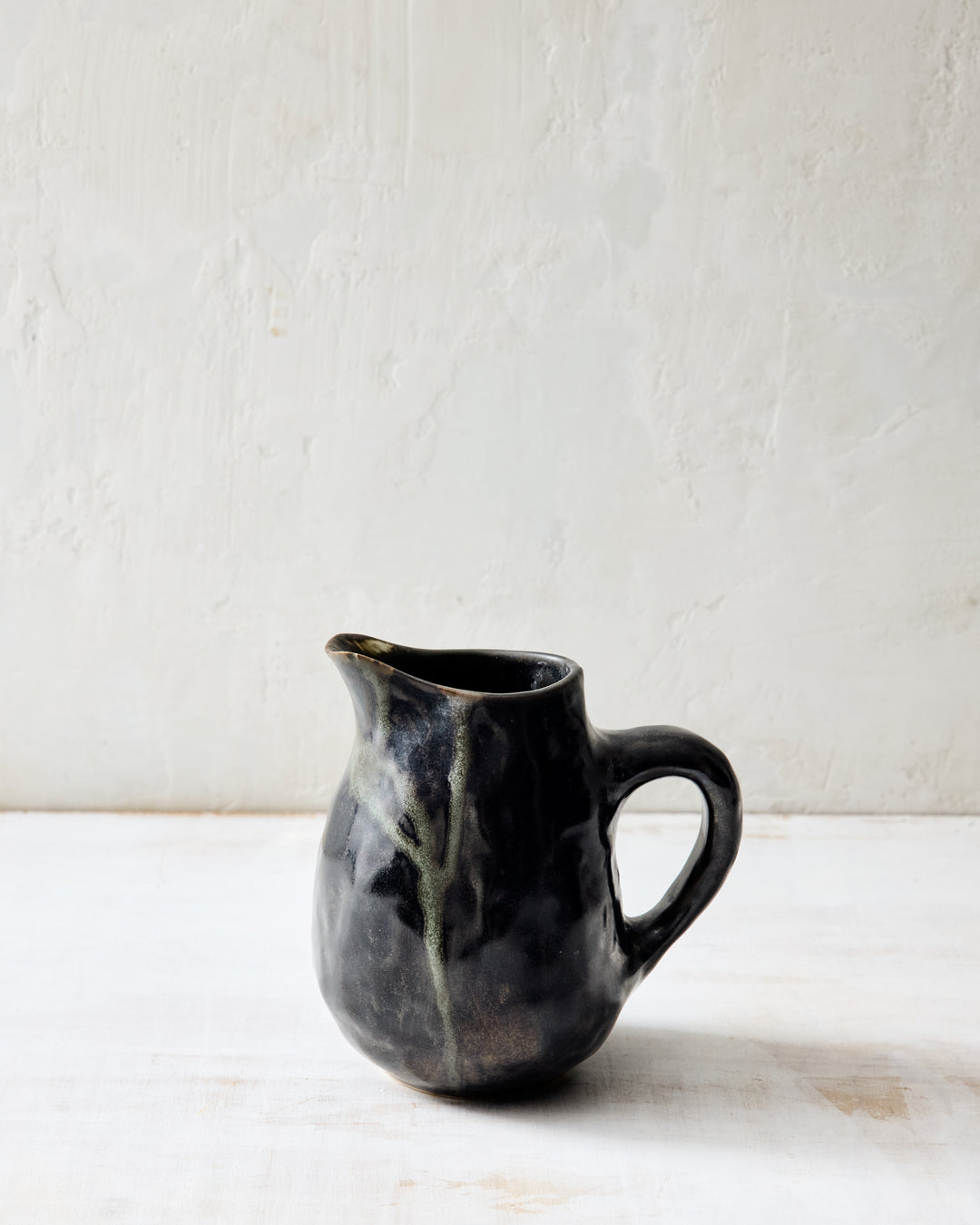 DBO HOME Wabi Pitcher in Granite glaze, handmade porcelain with a layered mussel and snowflake glaze and stone-like surface texture, front view on a whitewashed surface.