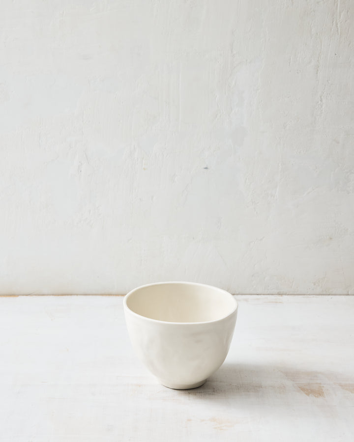 DBO HOME Wabi Rice Bowl in Foam glaze, handmade porcelain with a rounded form, subtle white-on-white layered glaze, and stone-like surface texture, photographed on a whitewashed surface.