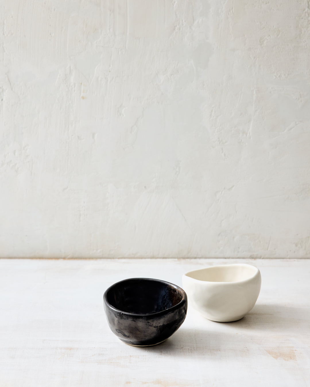 DBO HOME Wabi Salt Cellar in Granite and Foam glazes, handmade porcelain with stone-like surface texture, shown as a group of small bowls on a whitewashed surface.