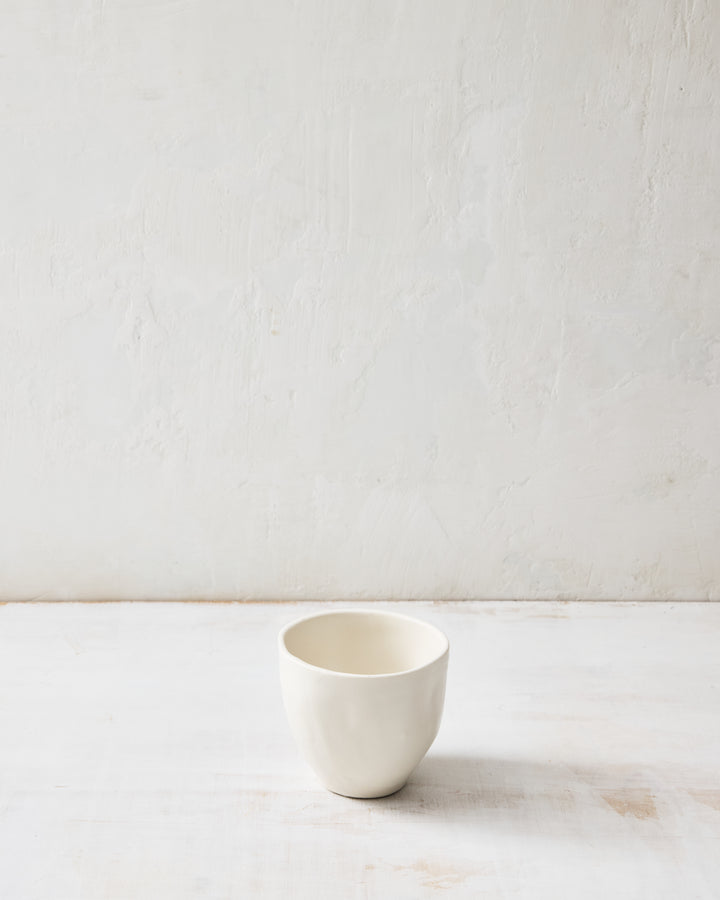 DBO HOME Wabi Tea Bowl in Foam glaze, handmade porcelain with a small rounded form, subtle white-on-white layered glaze, and stone-like surface texture, photographed on a whitewashed surface.