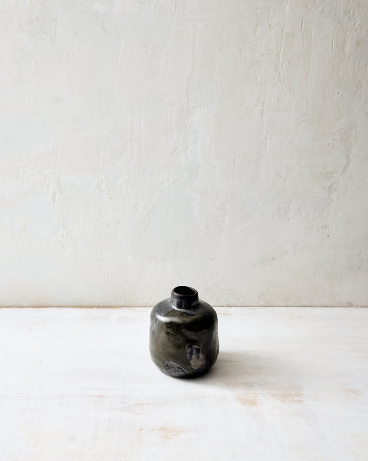 Short Wabi ceramic vase in Granite glaze, featuring a compact organic form and layered charcoal tones with natural glaze variation, photographed in a minimalist setting.