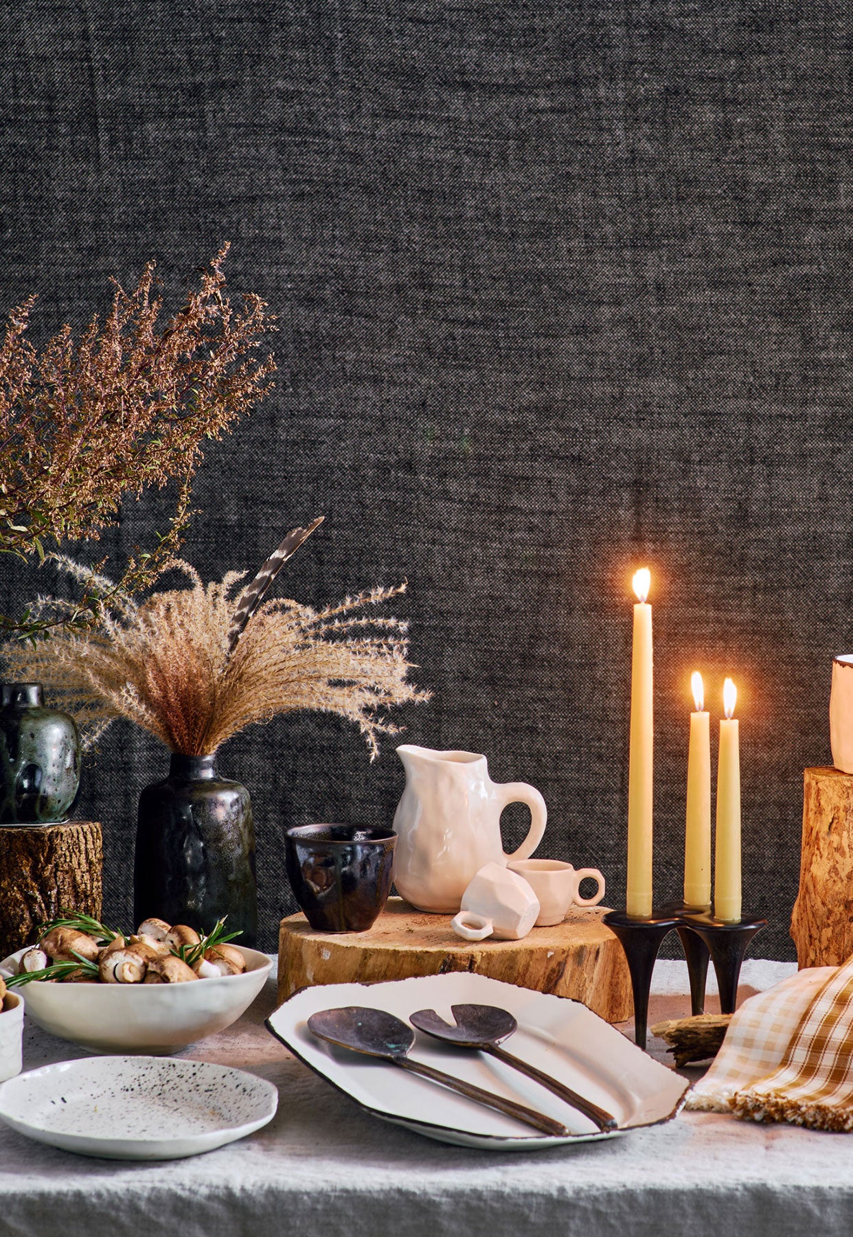 DBO HOME 2023 holiday gift guide spread of everyday luxury handmade ceramic and bronze pieces arranged on an elegant and rustic holiday table with lit candles and wood details
