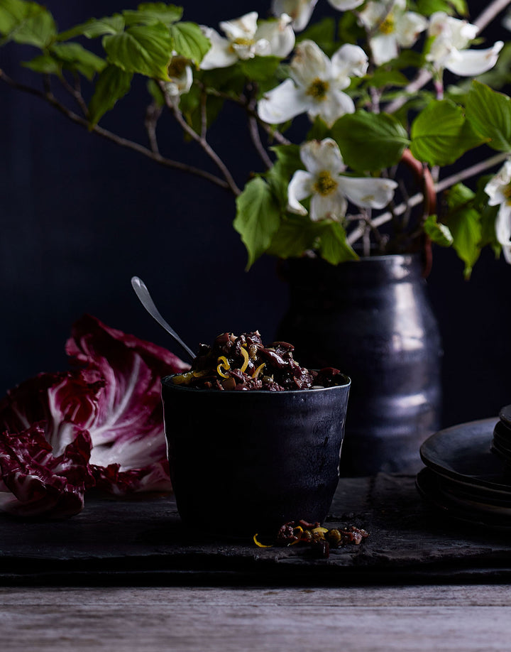 DBO HOME black handmade ceramic tumbler with dark food and bright flowers