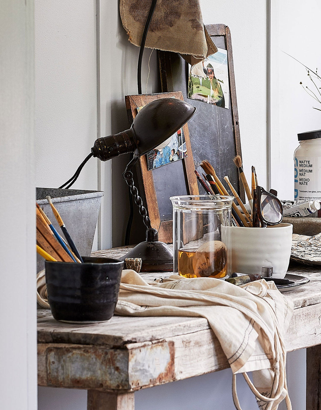 DBO HOME artisan ceramic cups on artist's table filled with paintbrushes and art supplies