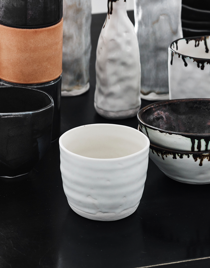Handcrafted porcelain white tumbler cup with artisan ceramic black and white bowls, mugs, and vases